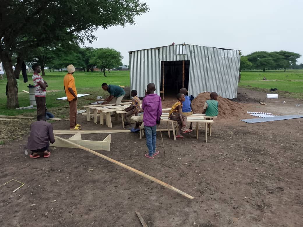 a group of people are working on a building in a field .
