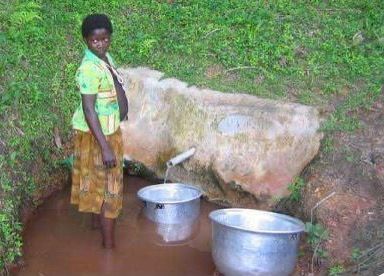 Lady getting water from a natural spring in Africa
