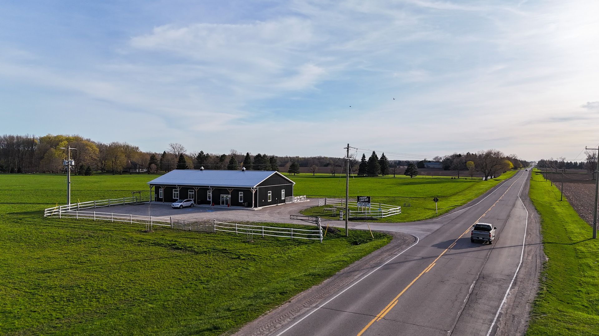 Black building with white trim, near a road, surrounded by green fields. mechanical and electrical engineering projects