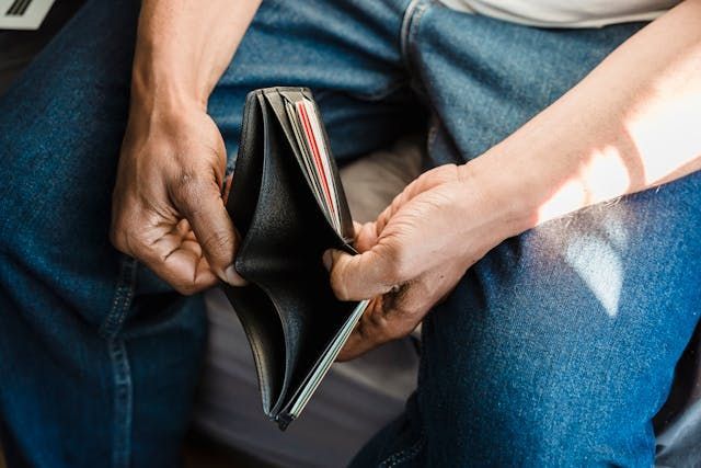 person-in-blue-jeans-holding-open-an-empty-wallet