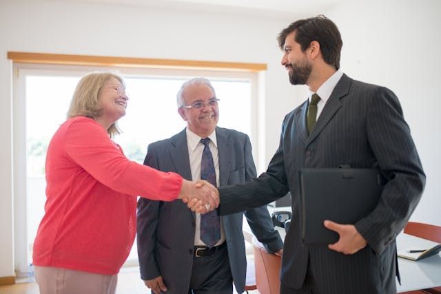 two+people+shaking+hands+with+real+estate+agent.