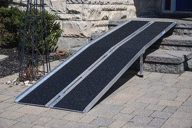 A wheelchair ramp is sitting on a brick sidewalk next to stairs.