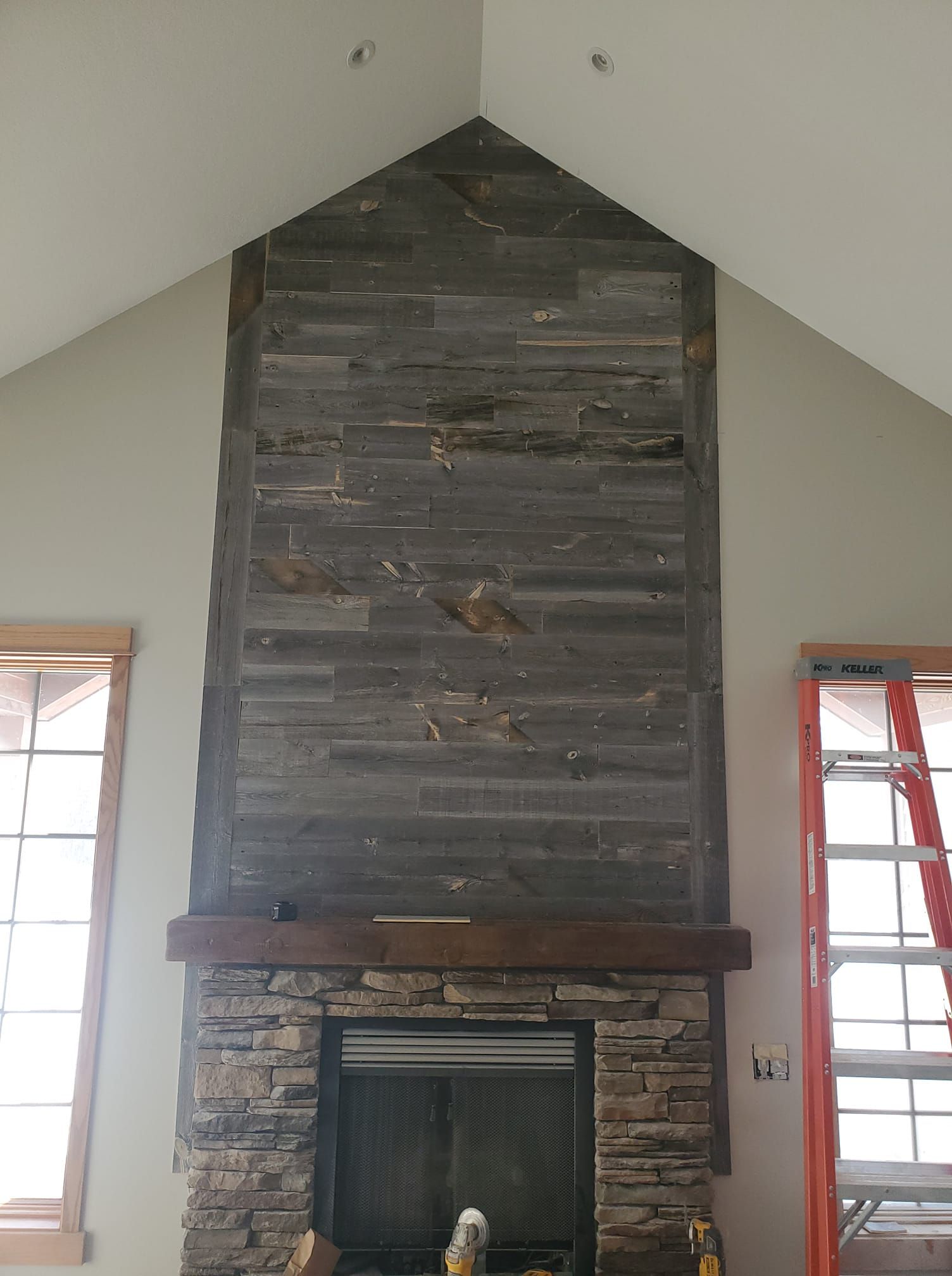 A large stone fireplace with a wooden mantle in a living room.