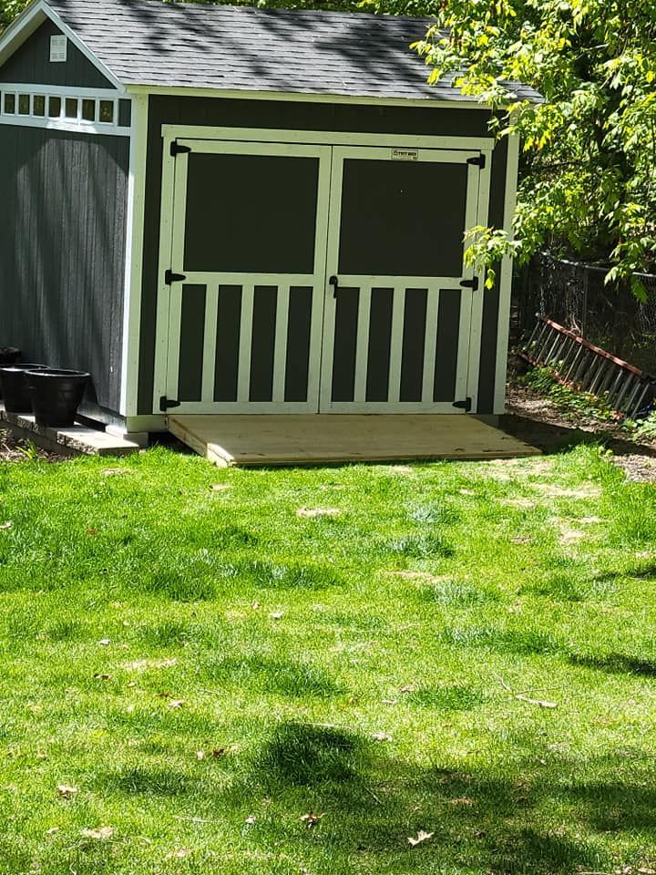 A shed is sitting in the middle of a lush green yard.