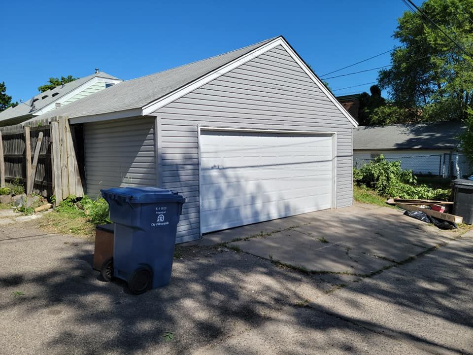 A trash can is sitting in front of a garage door.