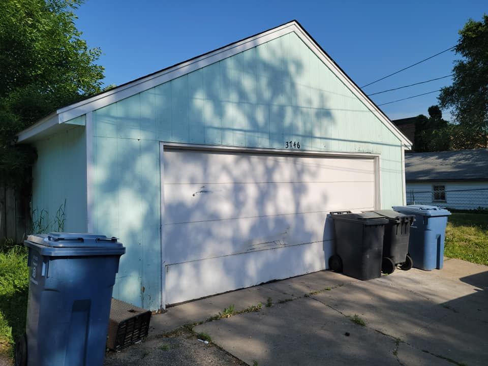 A garage with two trash cans in front of it