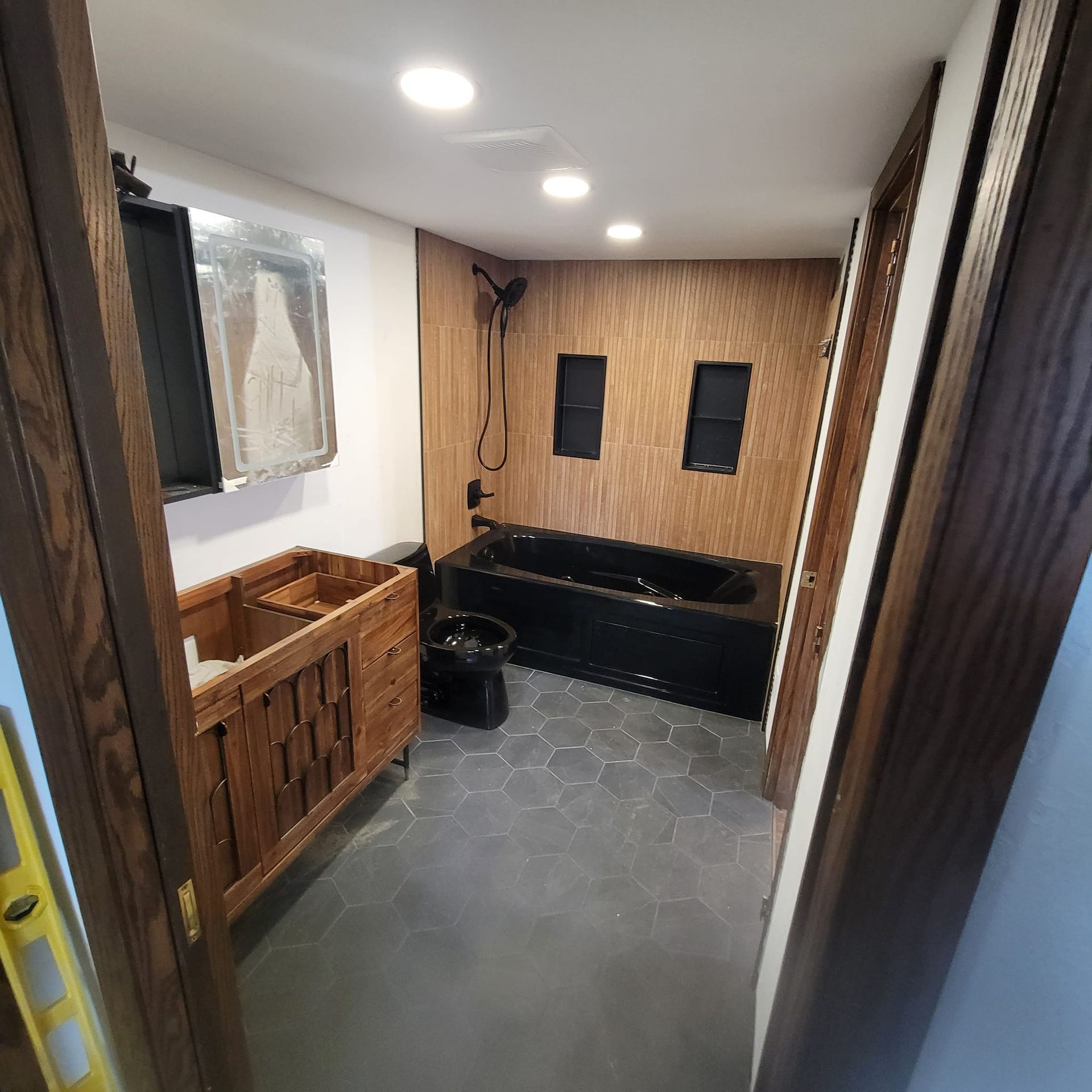 A bathroom with a black tub and a wooden vanity.