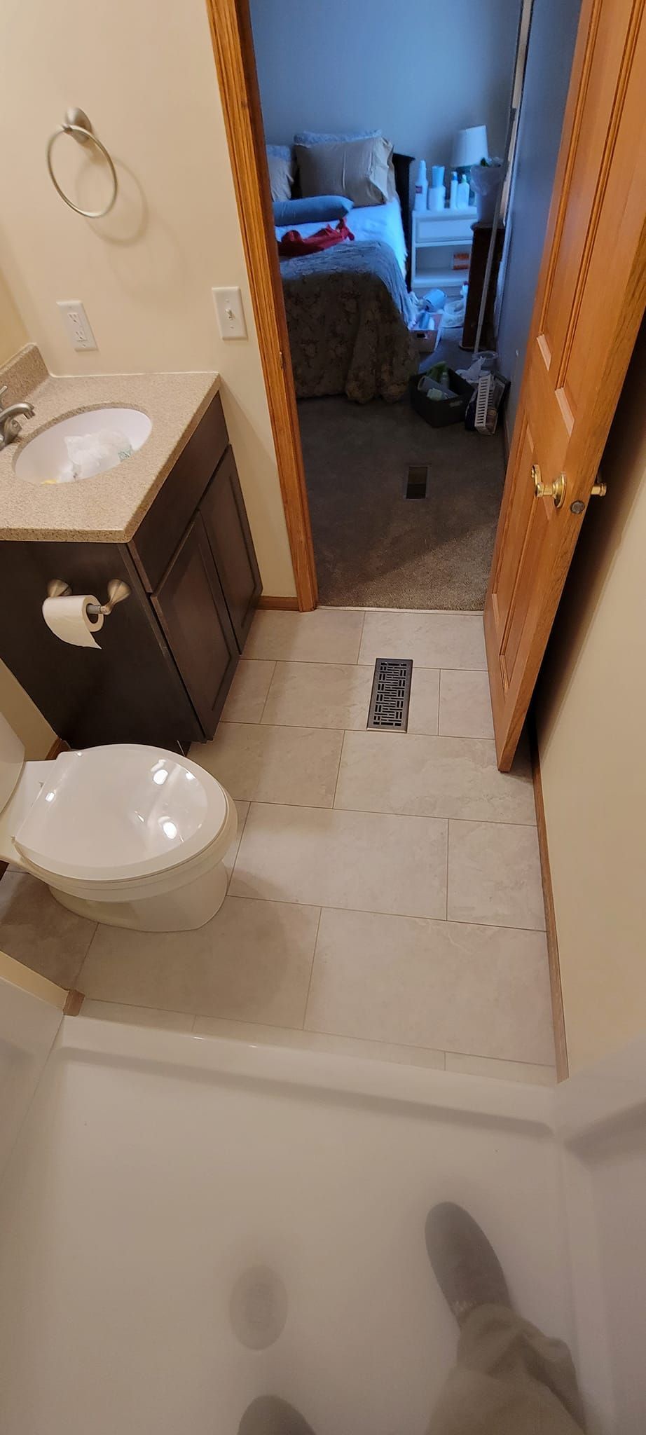 A bathroom with a toilet , sink , and door leading to a bedroom.