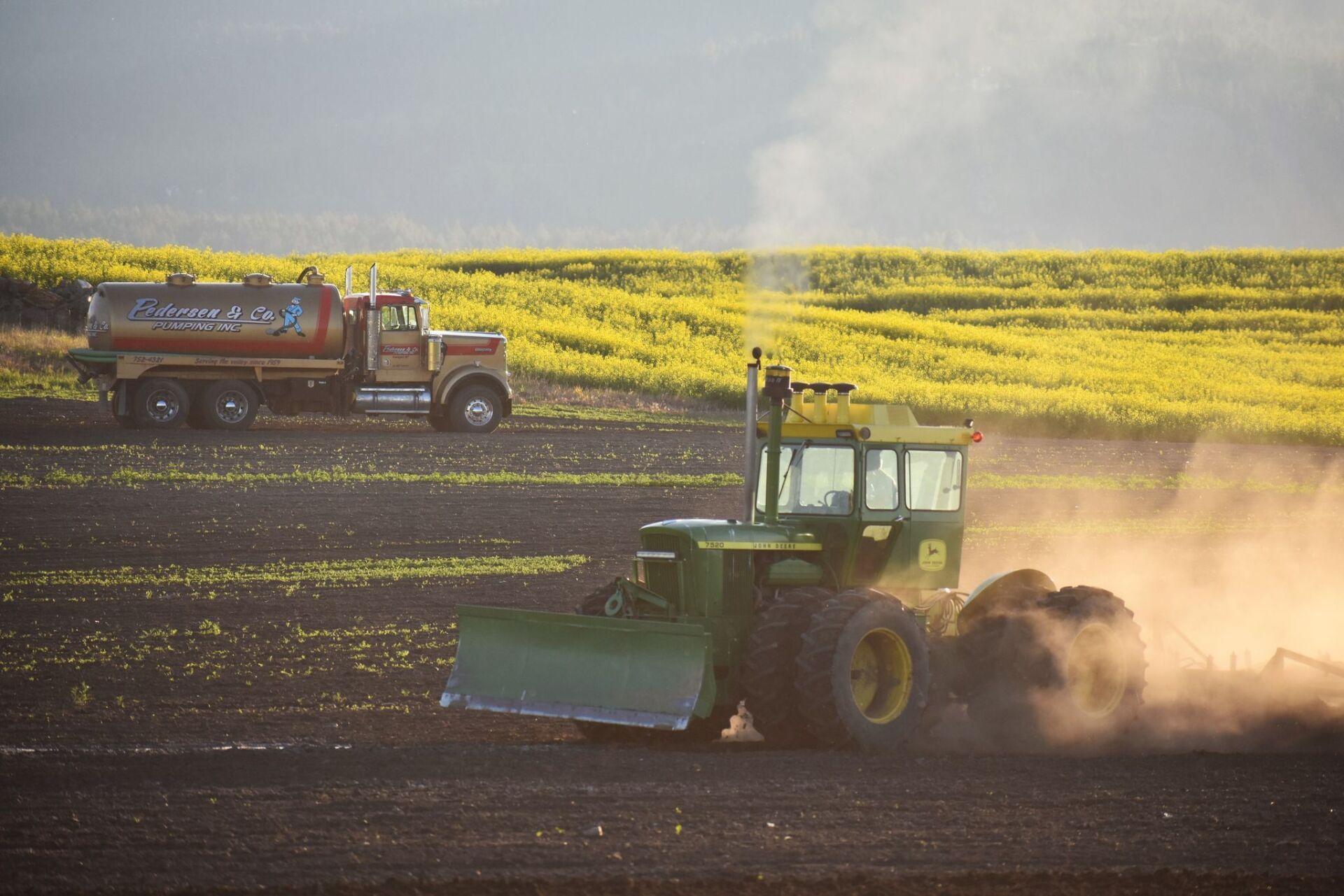 Tractor with a company vehicle at the back — Kalispell, MT — Pedersen & Co Pumping, Inc.