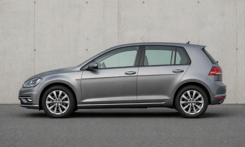 Side view of a silver VW TDI parked against a plain gray wall.