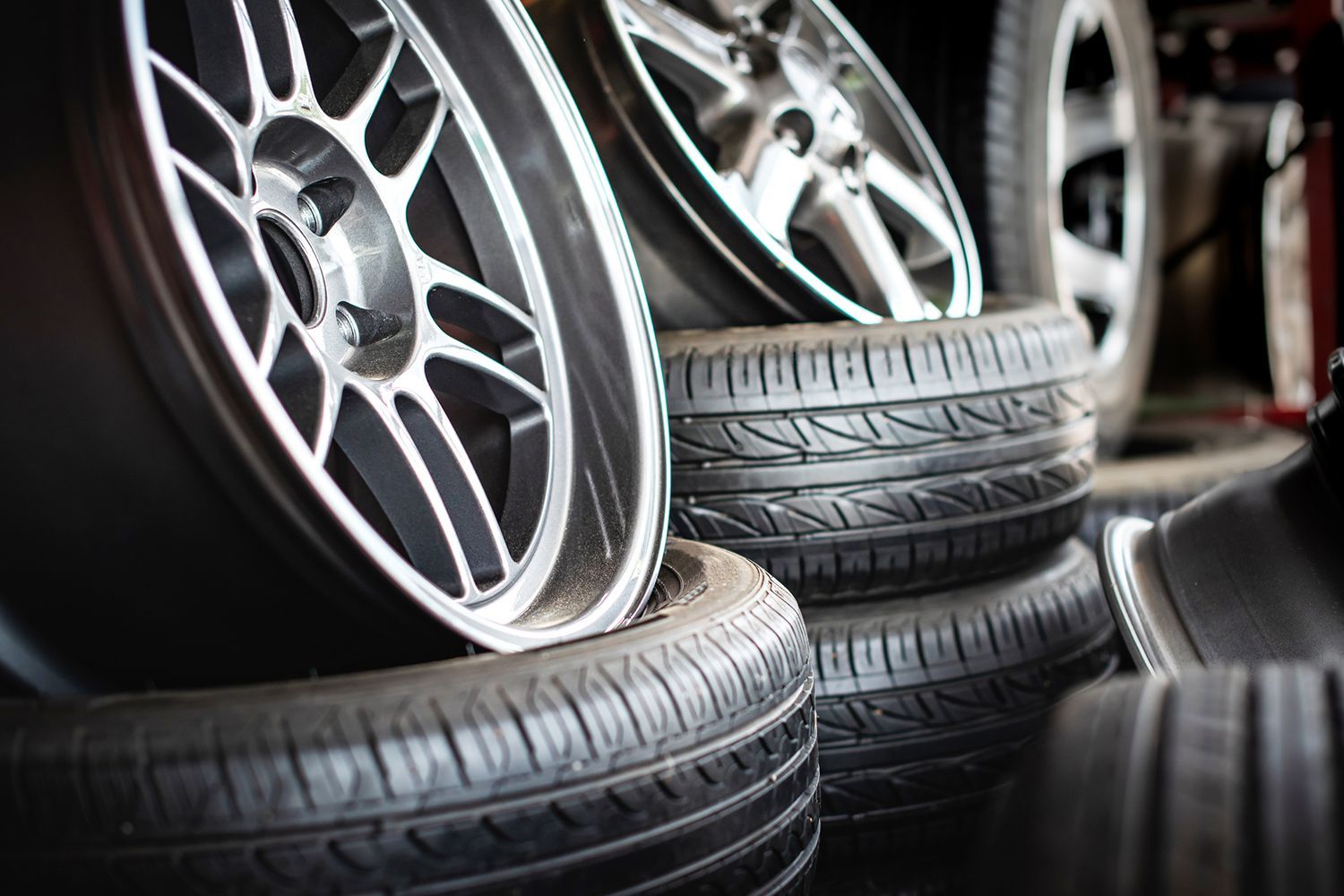 A stack of tires and wheels in a garage.