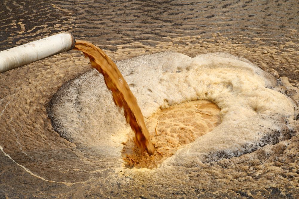Brown Liquid Pouring From a Pipe Into a Foamy, Circular Pool — Rosewood Environmental Services Pty Ltd in Taree, NSW
