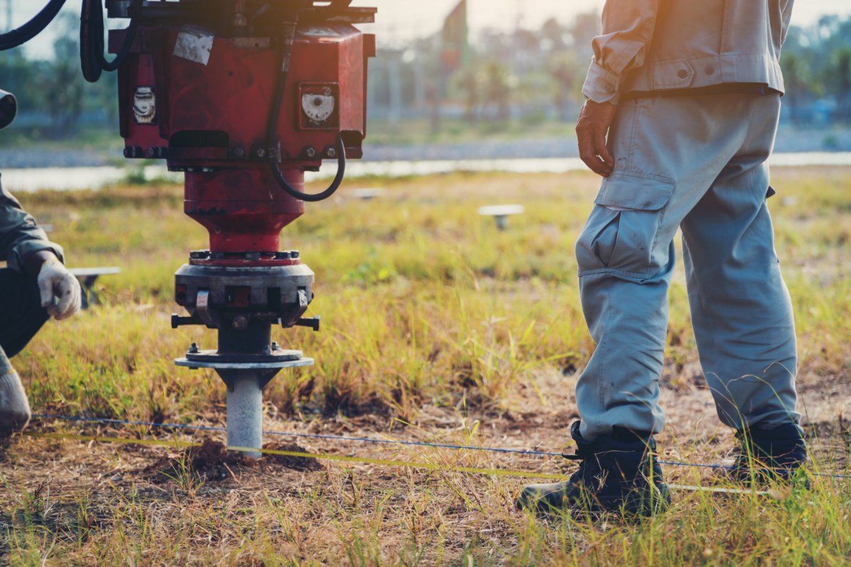 A Man Is Standing Next to A Machine in A Field — Rosewood Environmental Services Pty Ltd in Taree, NSW