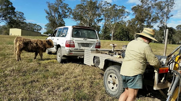 A Man Is Using a Drilling Equipment to Dig a Hole — Rosewood Environmental Services Pty Ltd in Port Macquarie, NSW