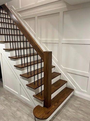 A wooden staircase with white walls and a wooden railing.