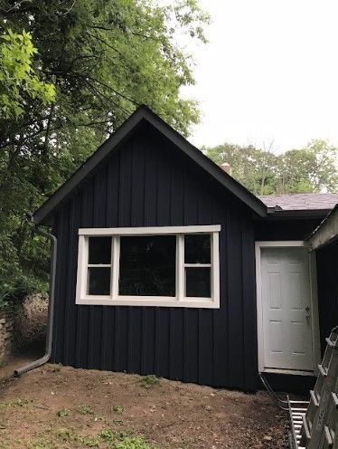 A small black house with a white door and window.