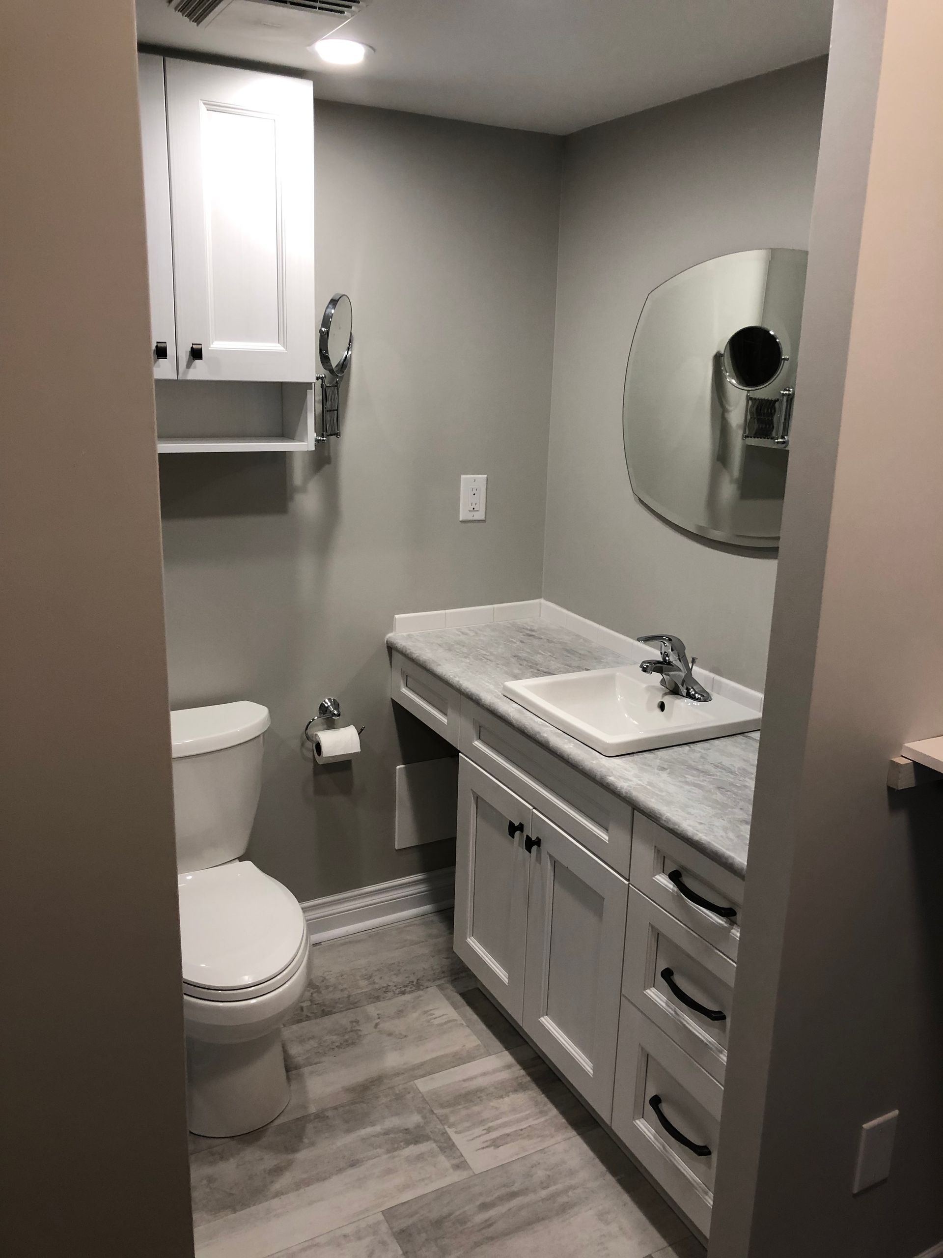 A bathroom with a toilet, sink and mirror.