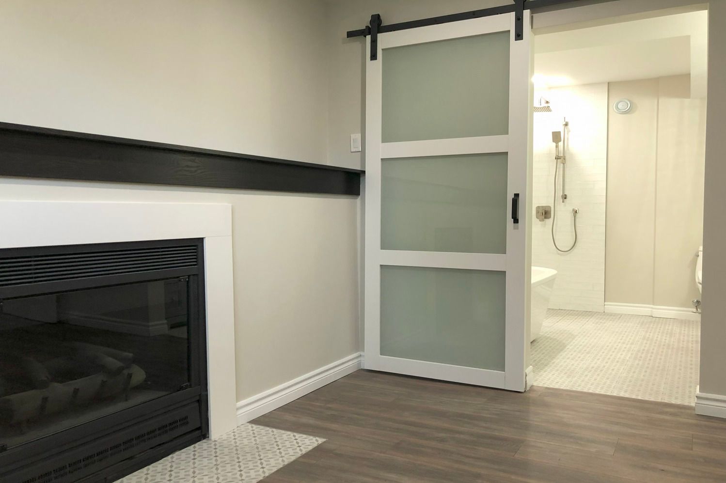 A living room with a fireplace and a sliding barn door leading to a bathroom.