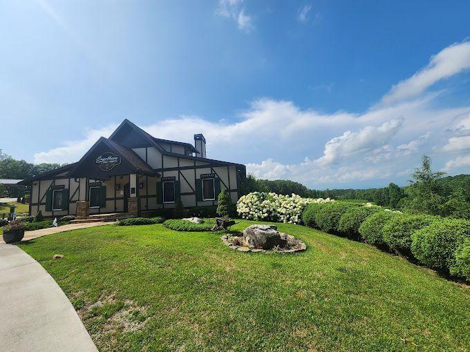 A large house is sitting on top of a lush green hill.