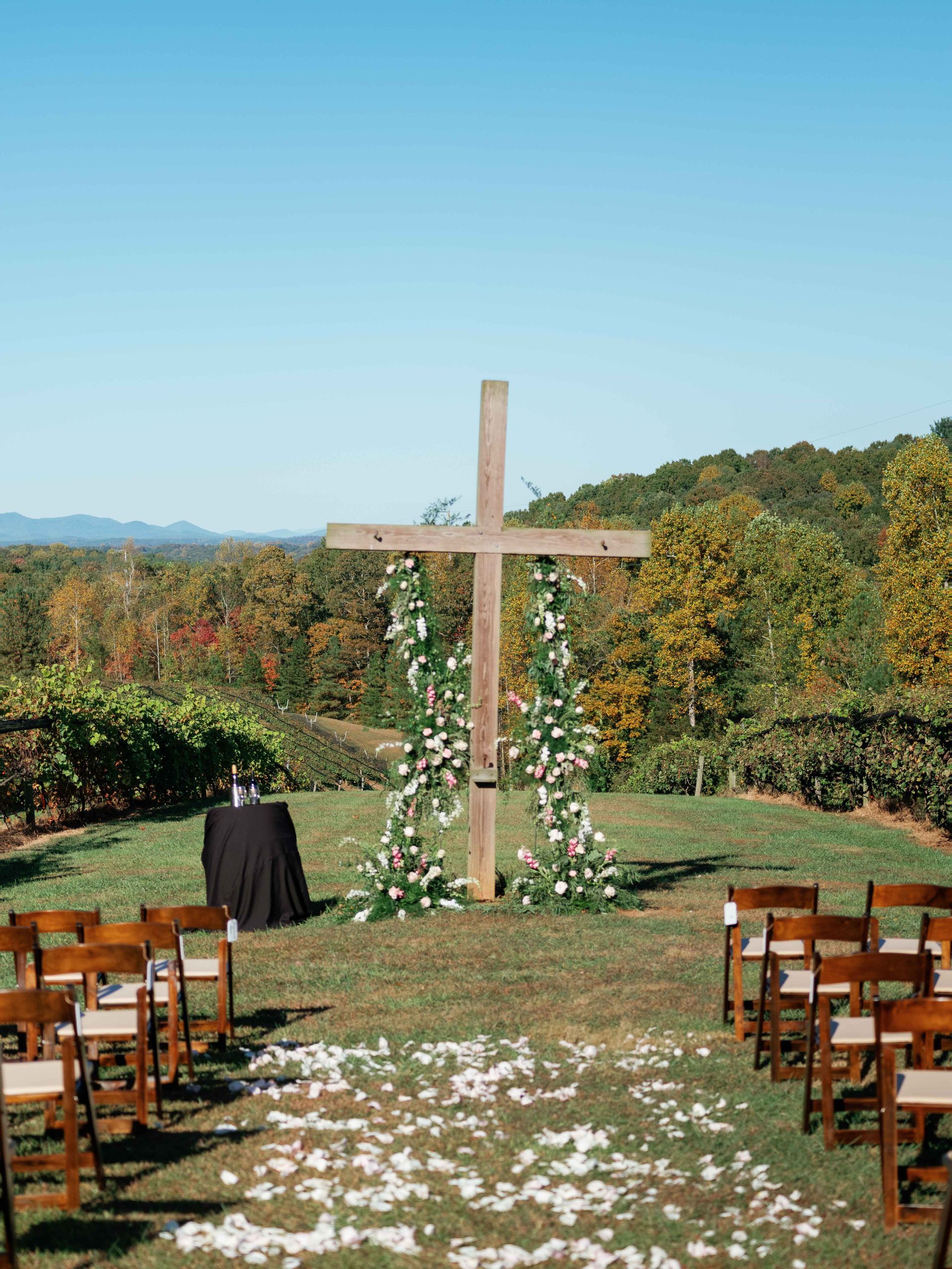 A wooden cross in the middle of a field with chairs in front of it