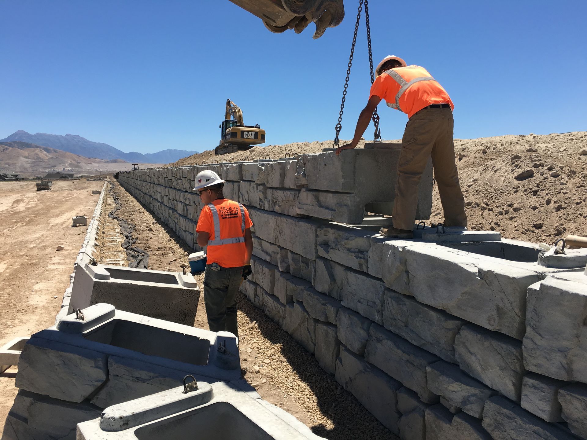 Two construction workers are working on a concrete wall.