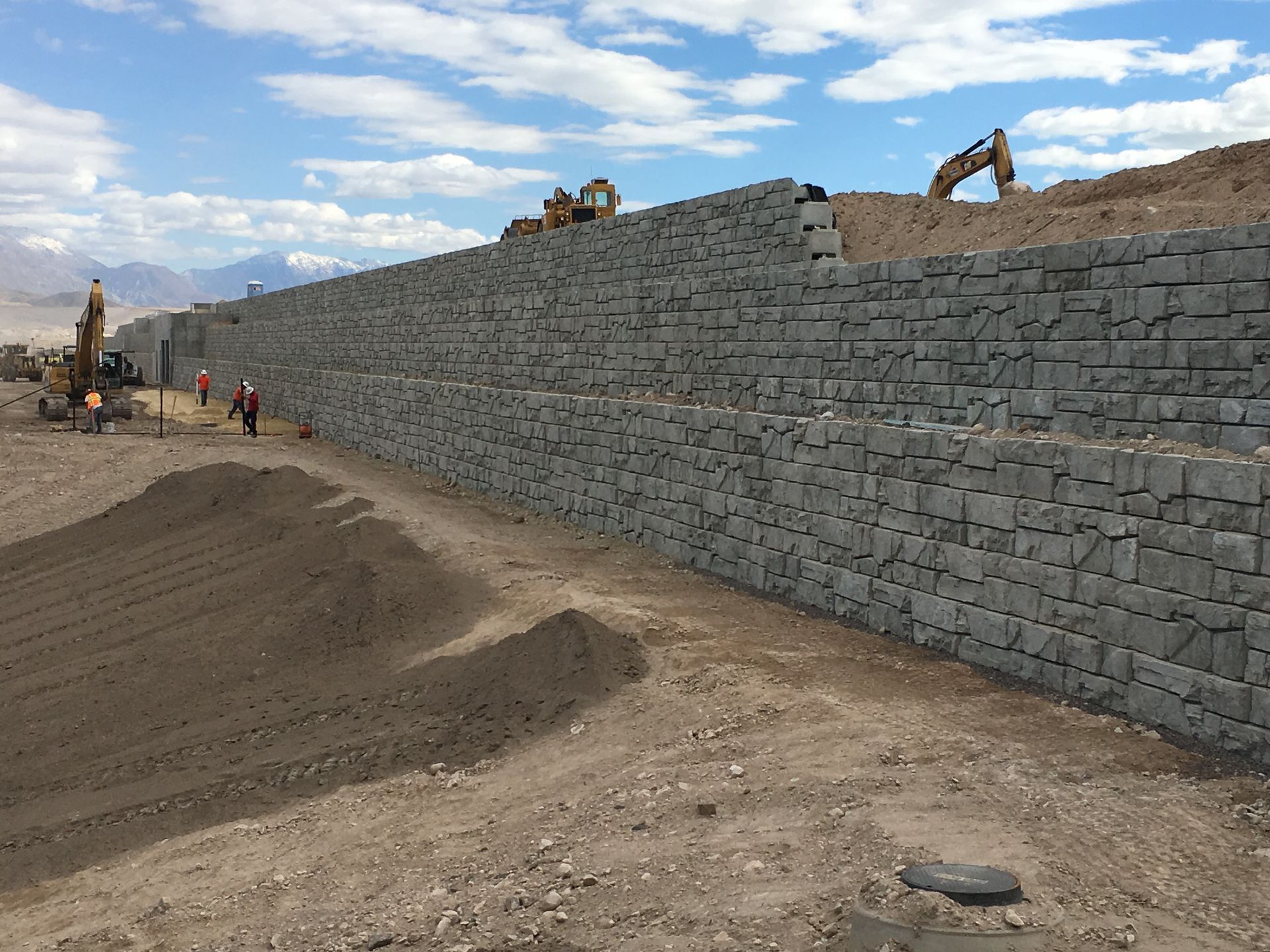 A large stone wall is being built in the middle of a dirt field.