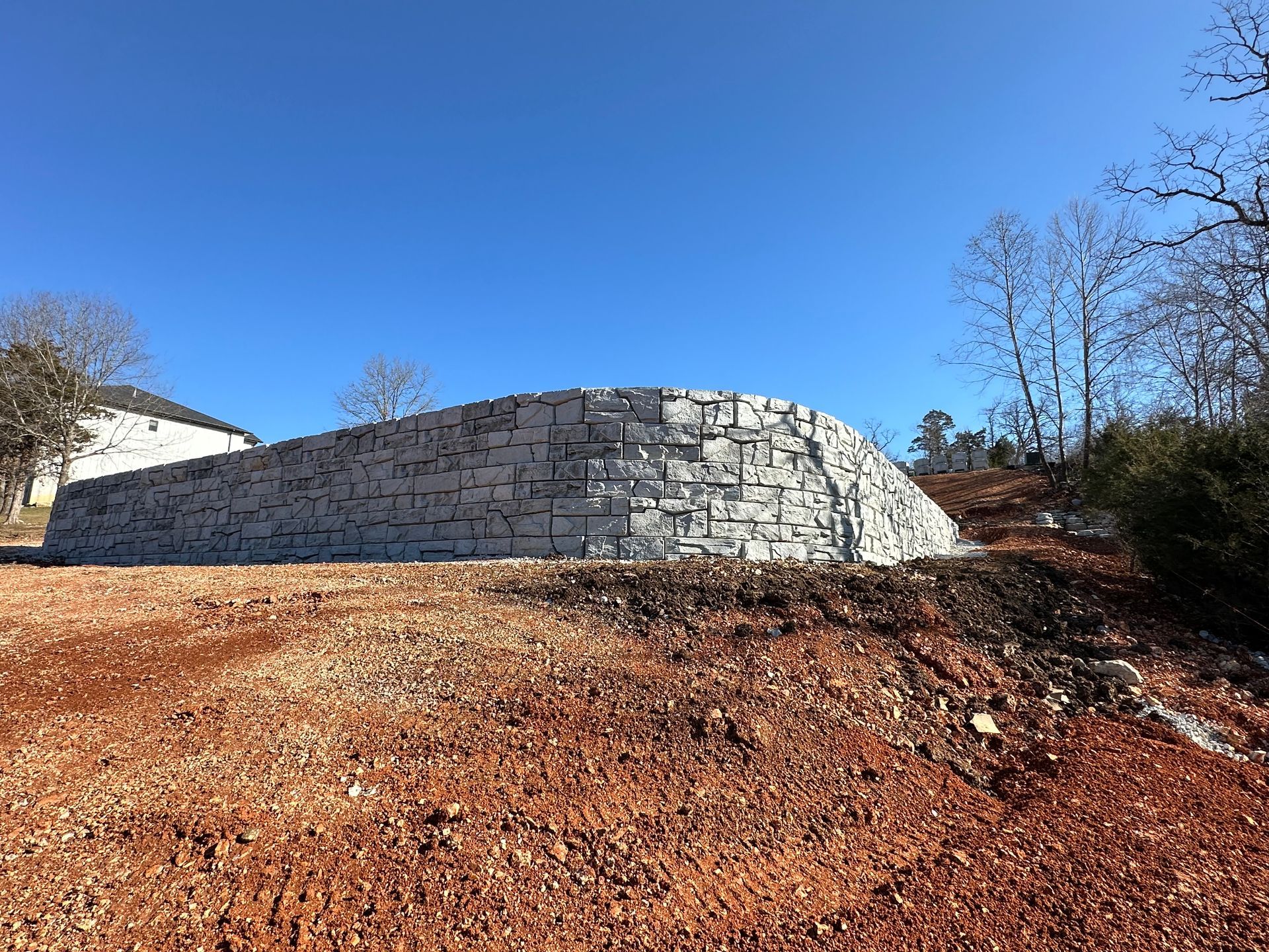 A large stone wall is sitting in the middle of a dirt field.