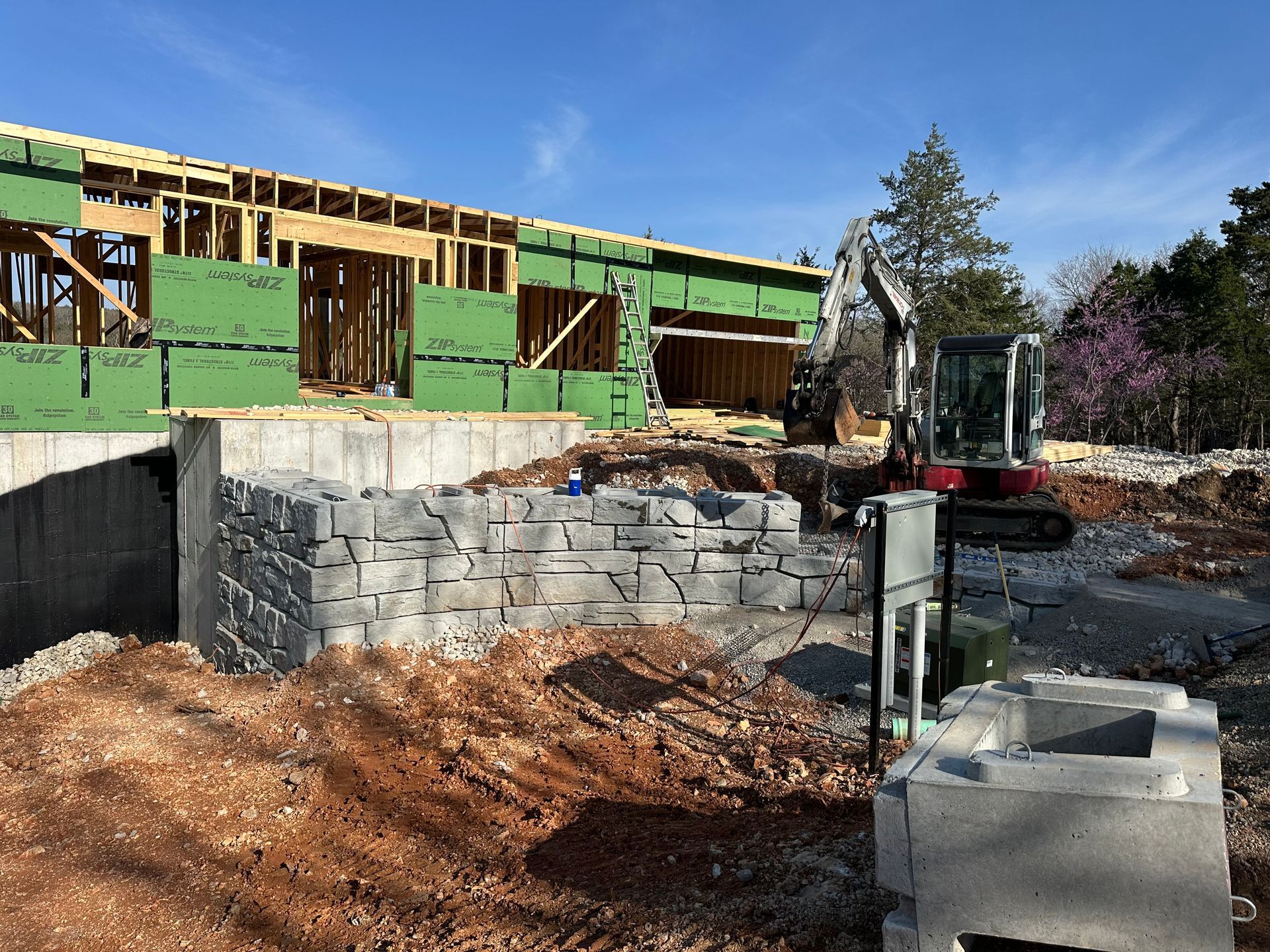 A construction site with a house under construction and a bulldozer in the foreground.