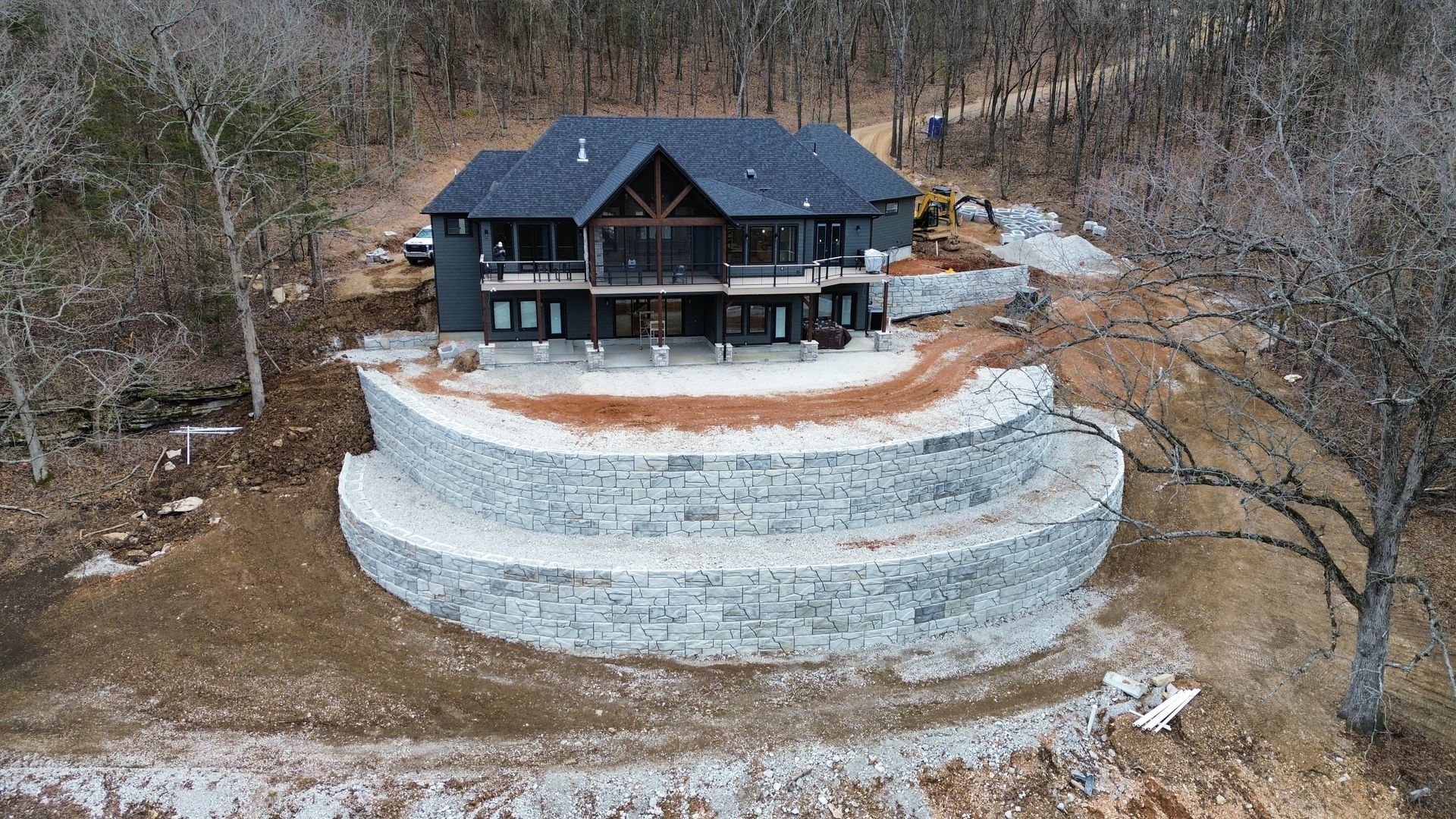 An aerial view of a large house sitting on top of a hill surrounded by trees.