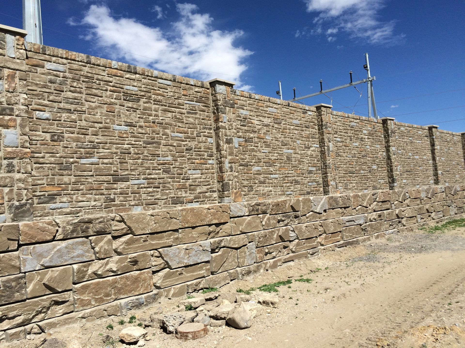 A large stone wall surrounds a dirt road.