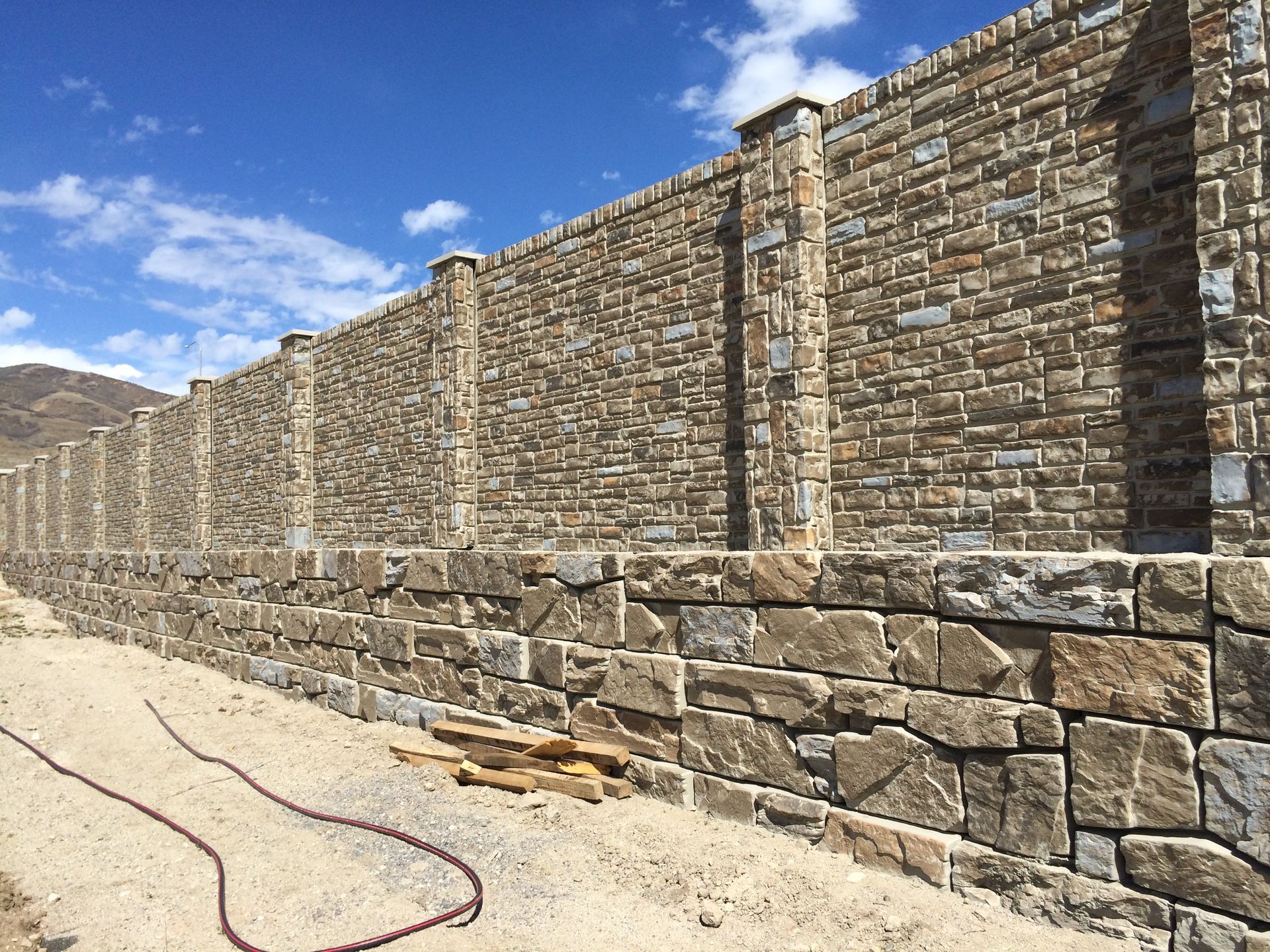 A large stone wall with a hose attached to it.