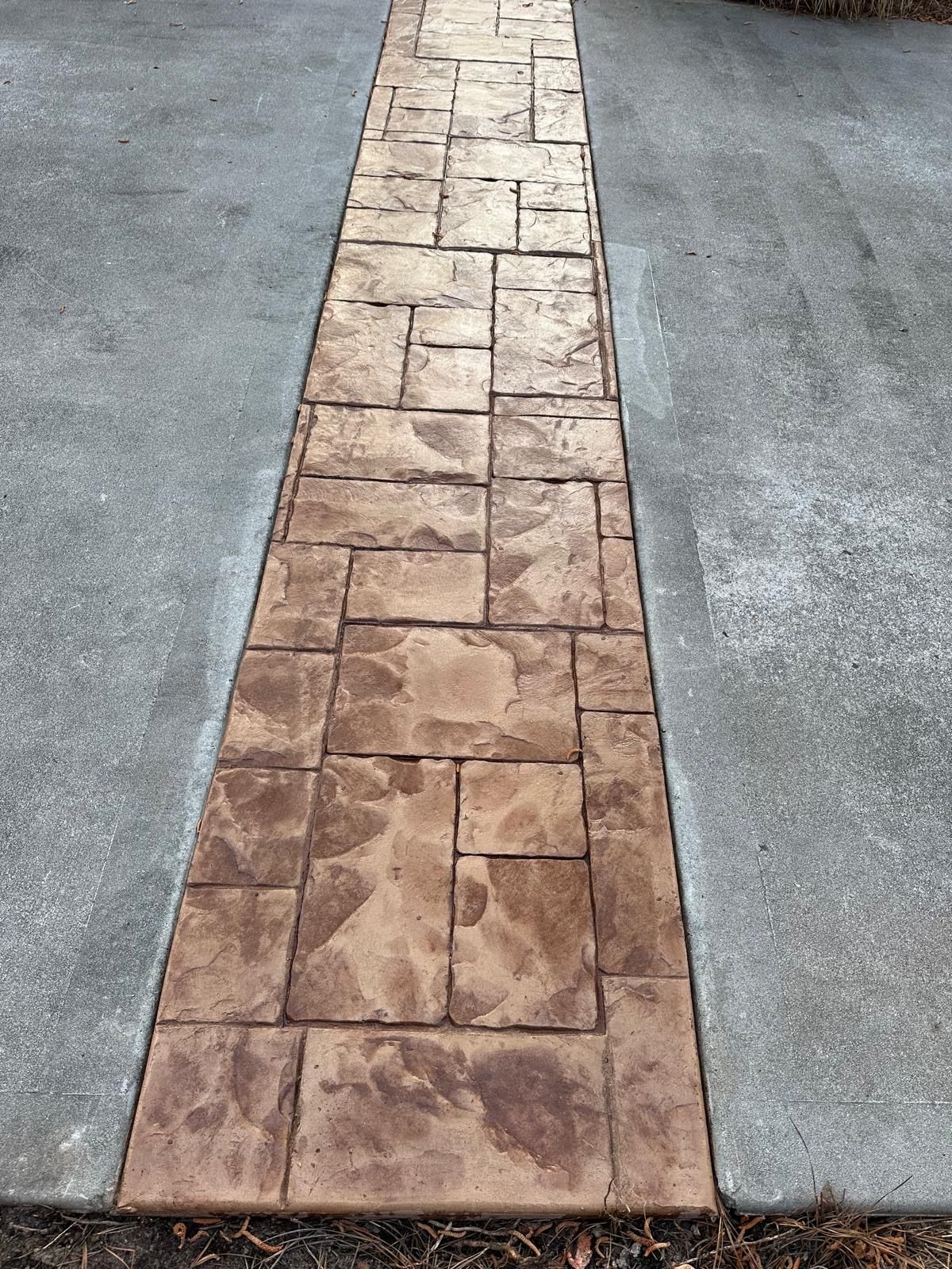 A concrete walkway with a brick pattern on it.
