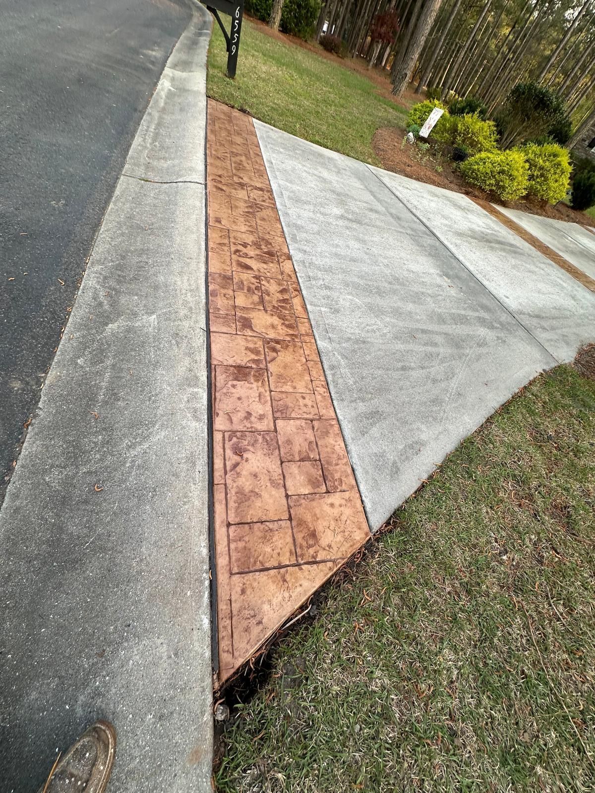 A concrete sidewalk with a brick pattern is next to a road.