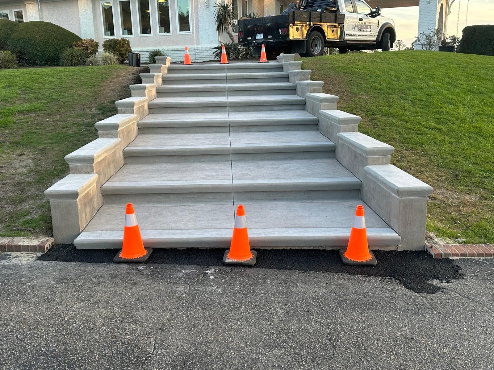 A set of concrete steps with orange cones on the side of the road.