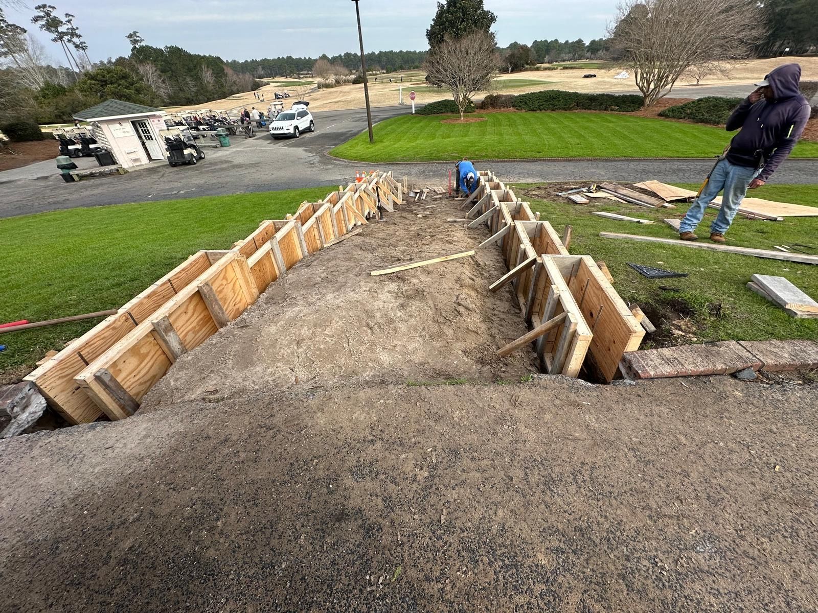 A man is standing next to a concrete staircase being built on a golf course.