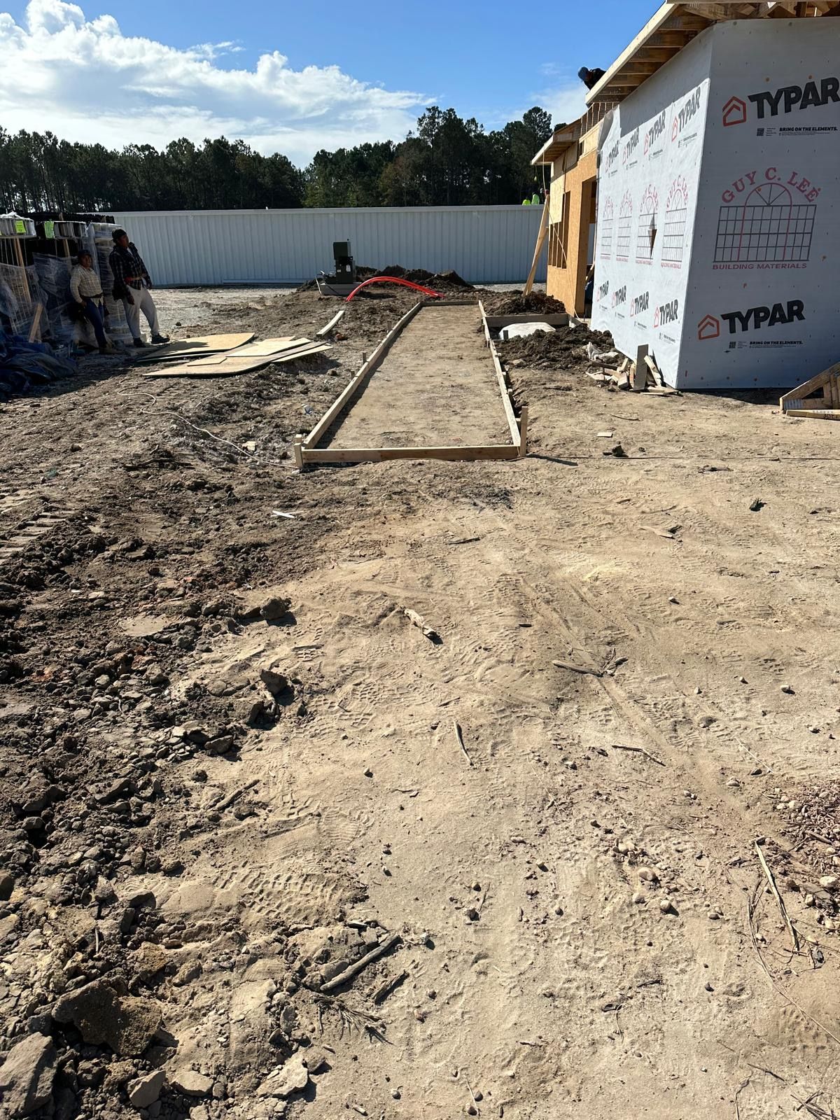 A dirt road leading to a building under construction.