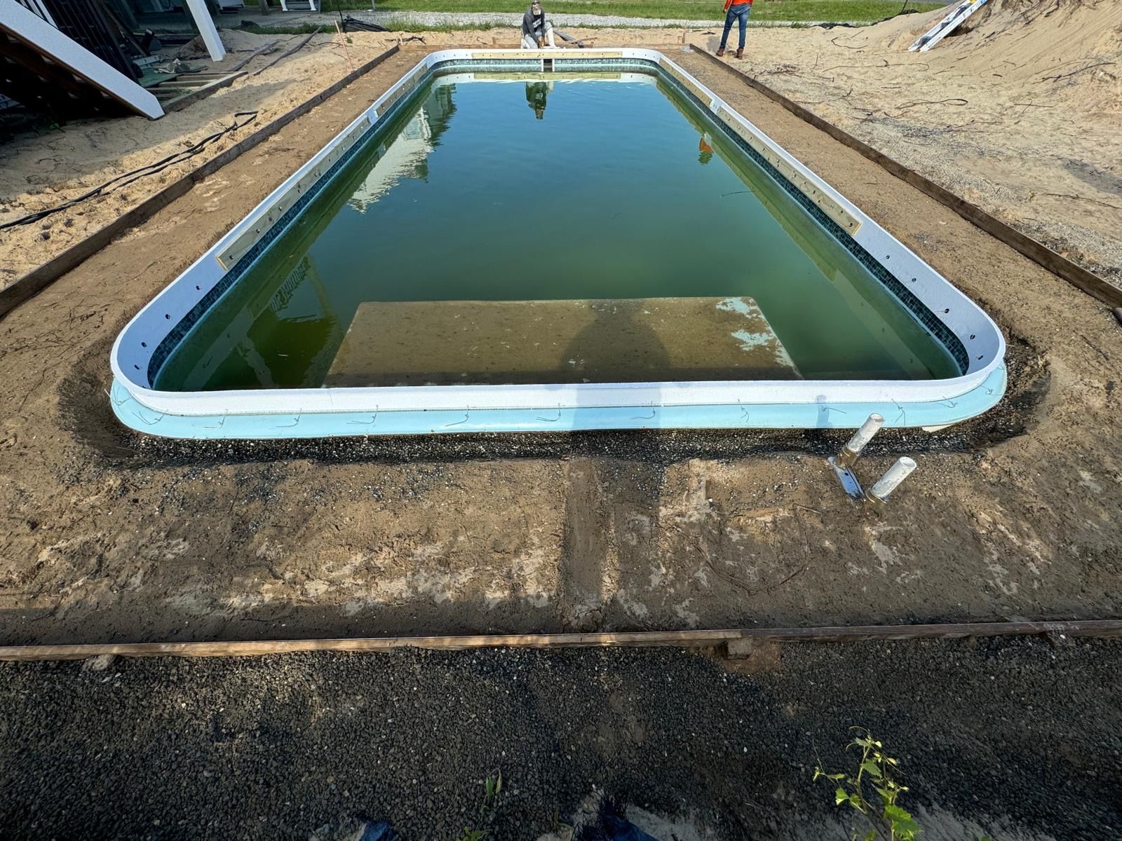A large swimming pool is being built in the dirt.