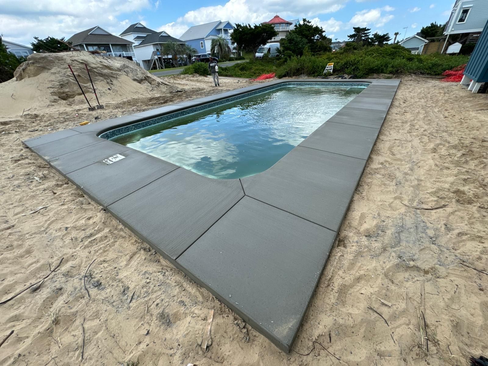 A large swimming pool is being built in the sand.