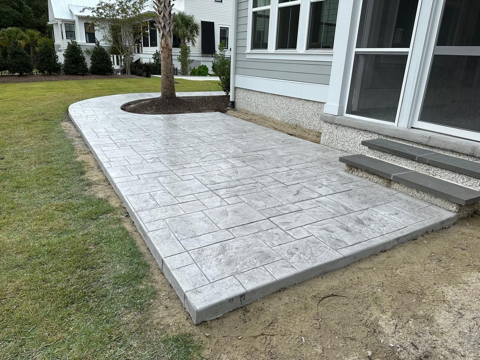 A concrete walkway leading to a screened in porch next to a house.