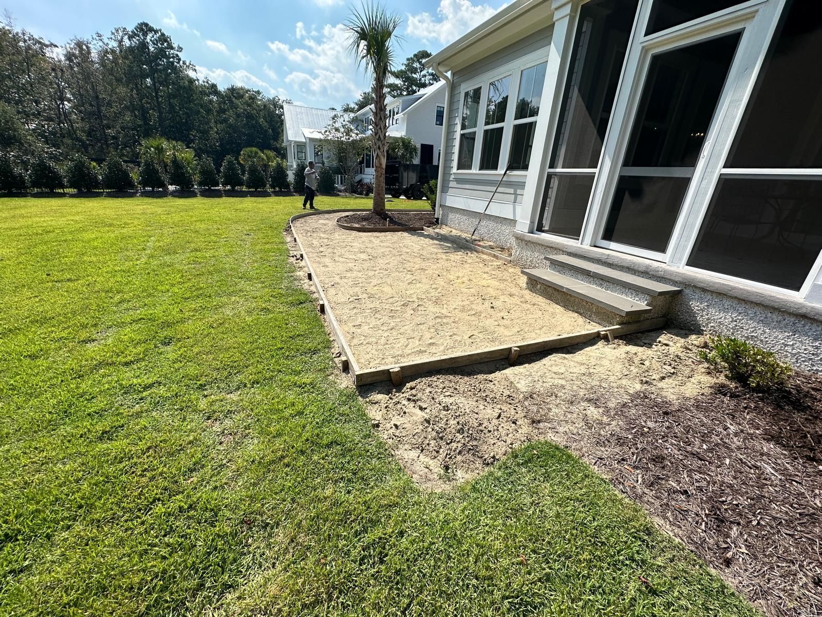 A house with a screened in porch and a large lawn in front of it.