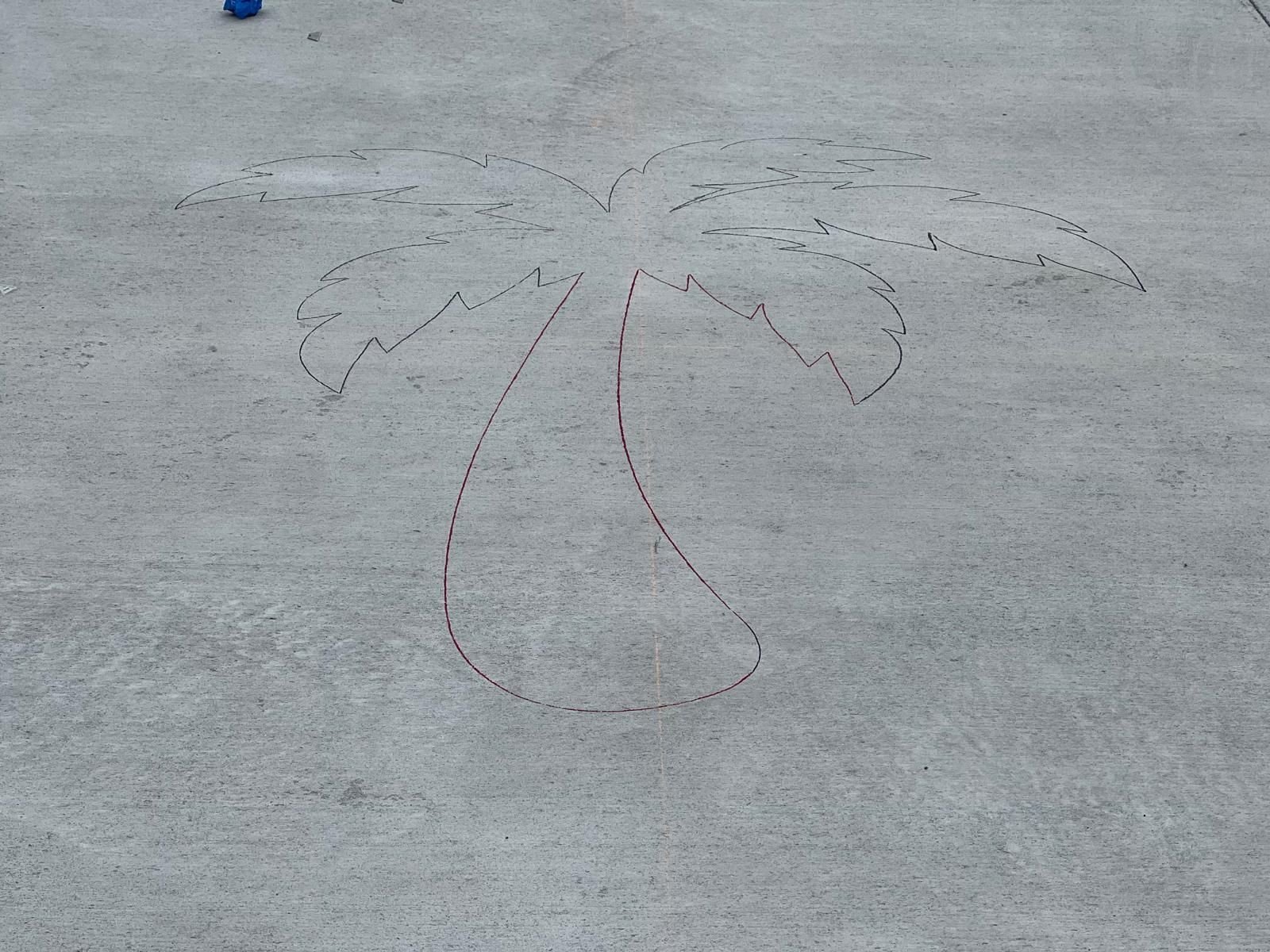 A drawing of a palm tree on a concrete surface