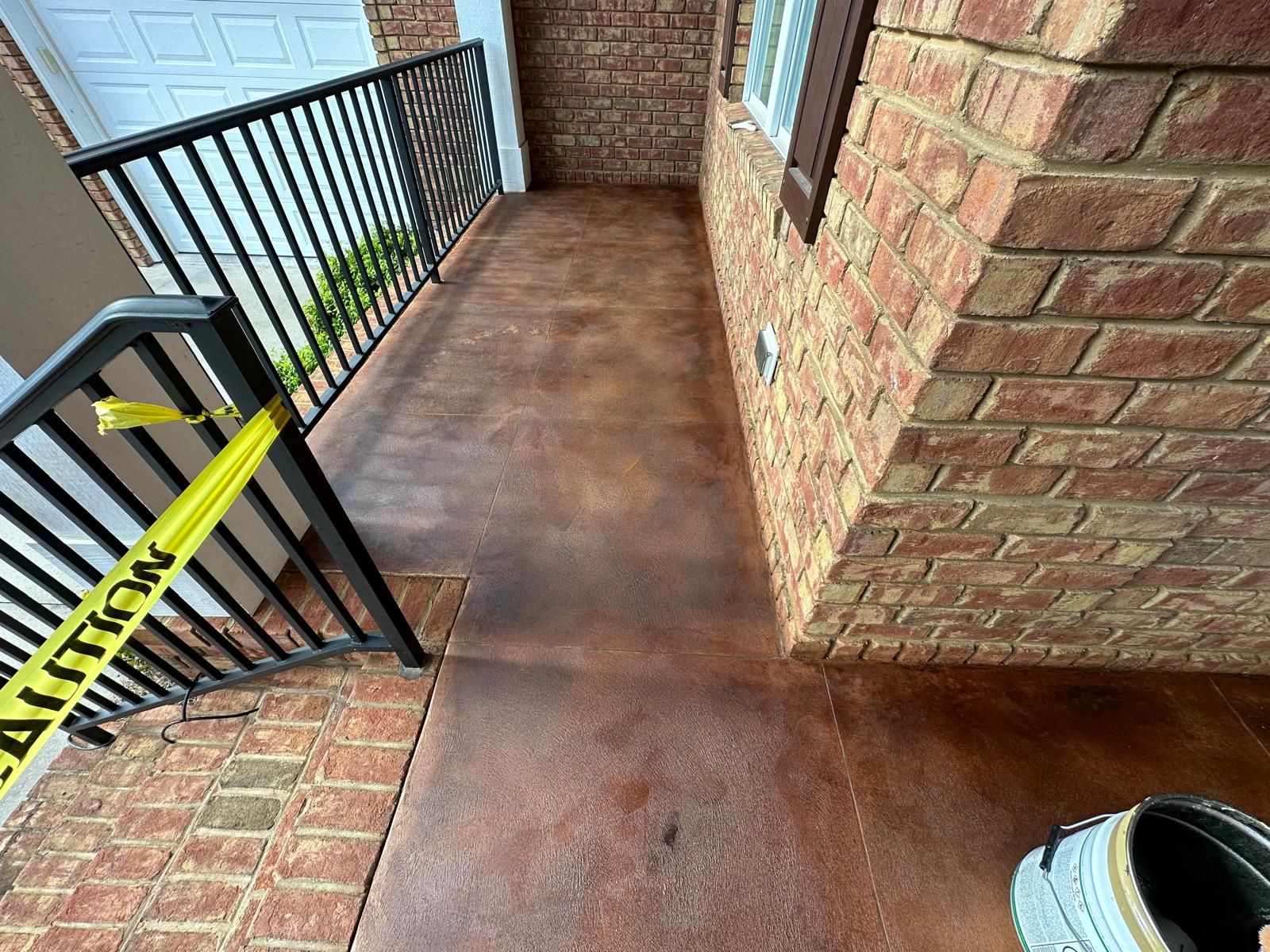 A brick building with a stained concrete walkway next to it.