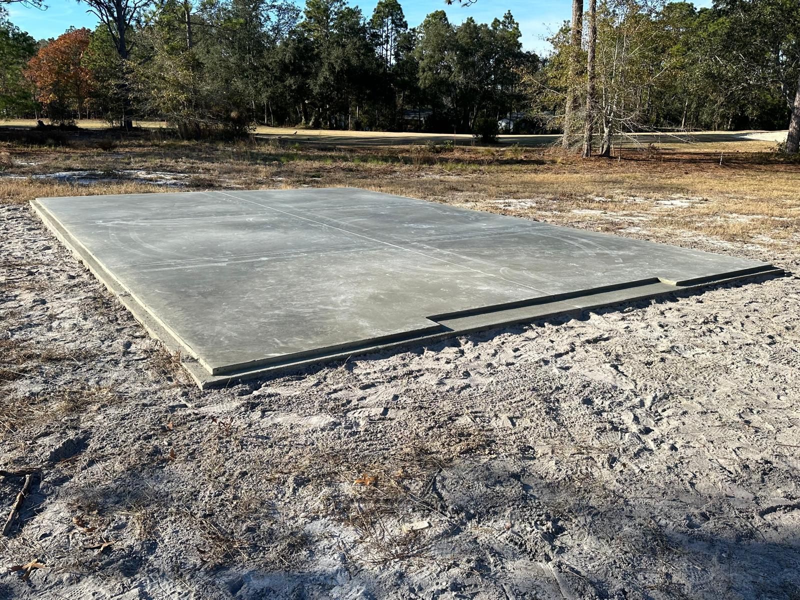 A large concrete slab is sitting in the middle of a dirt field.