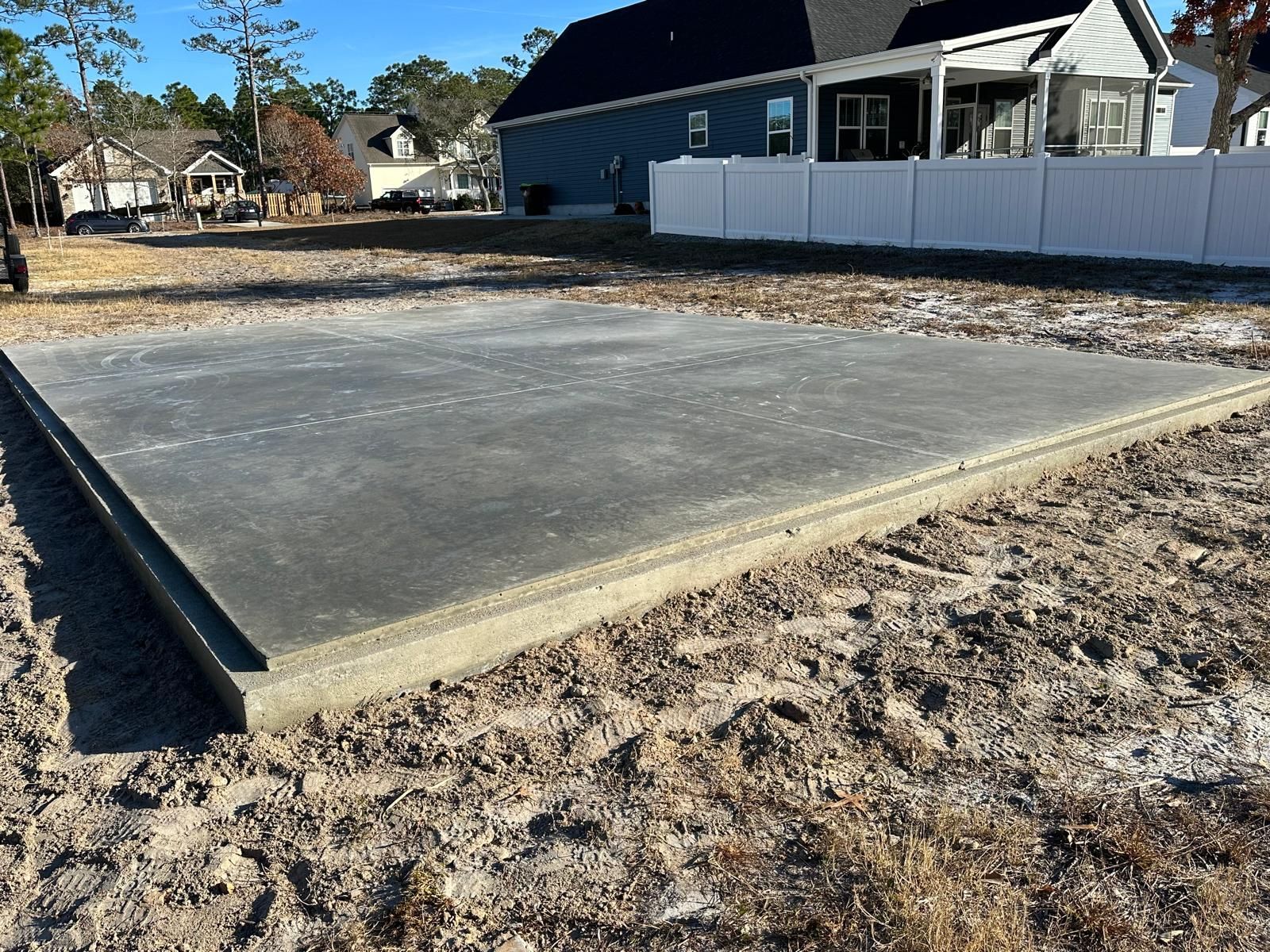 A concrete slab is sitting in the dirt in front of a house.