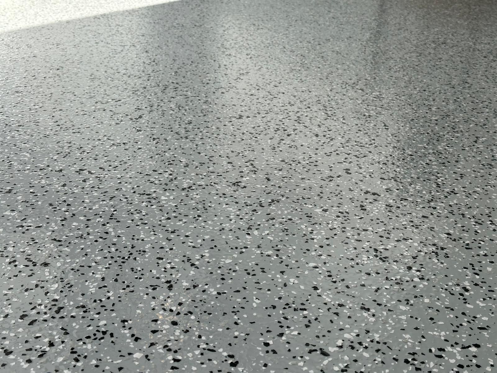 A close up of a gray floor with black and white specks