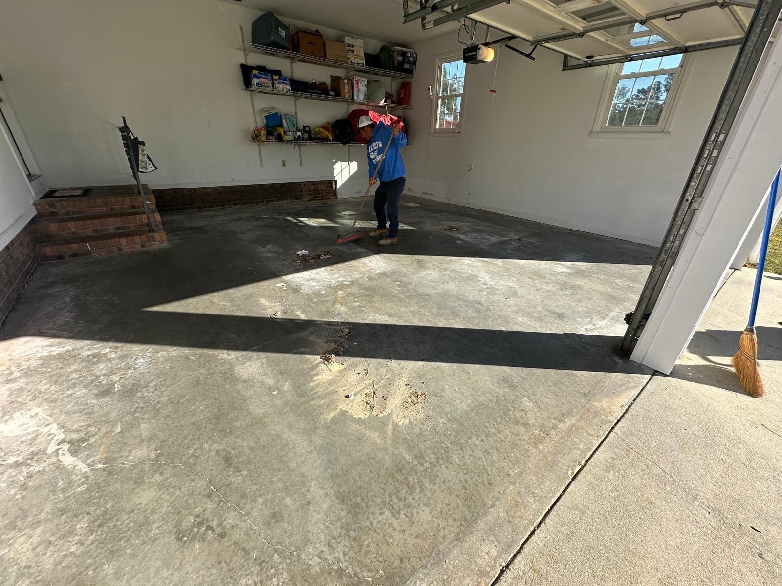 A child is standing in a garage with a broom.