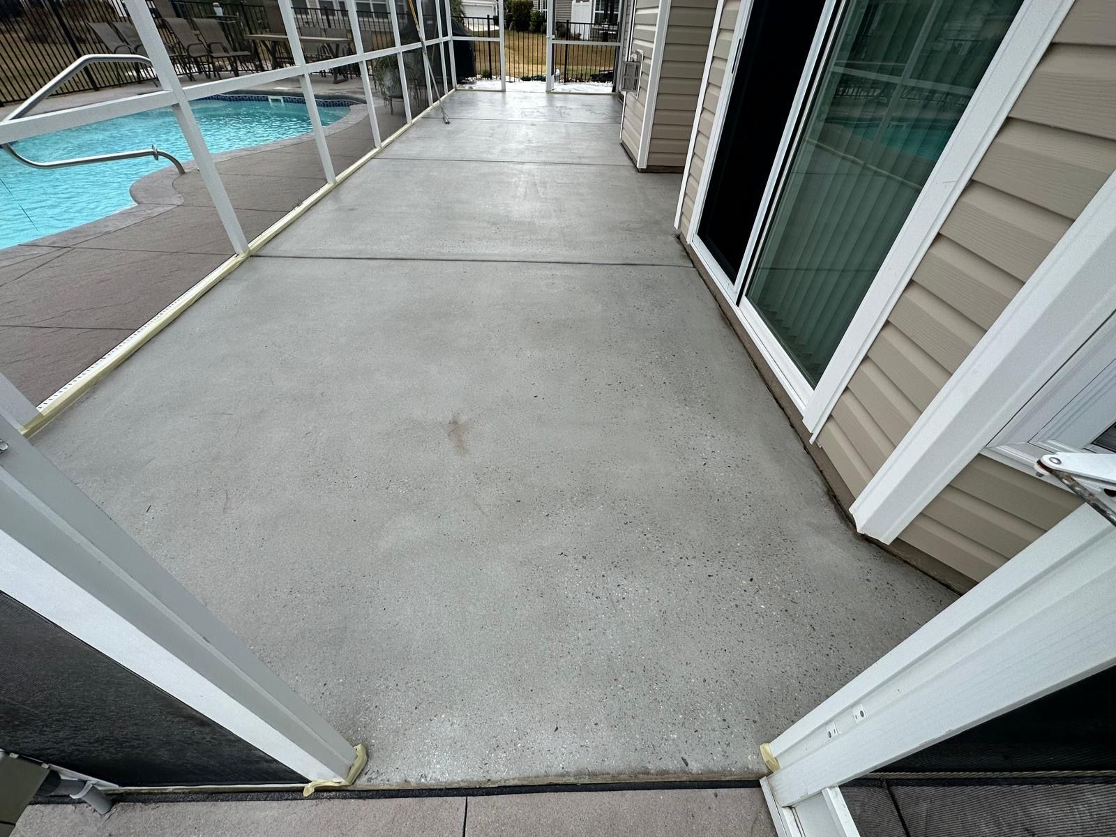 A screened in porch with a swimming pool in the background