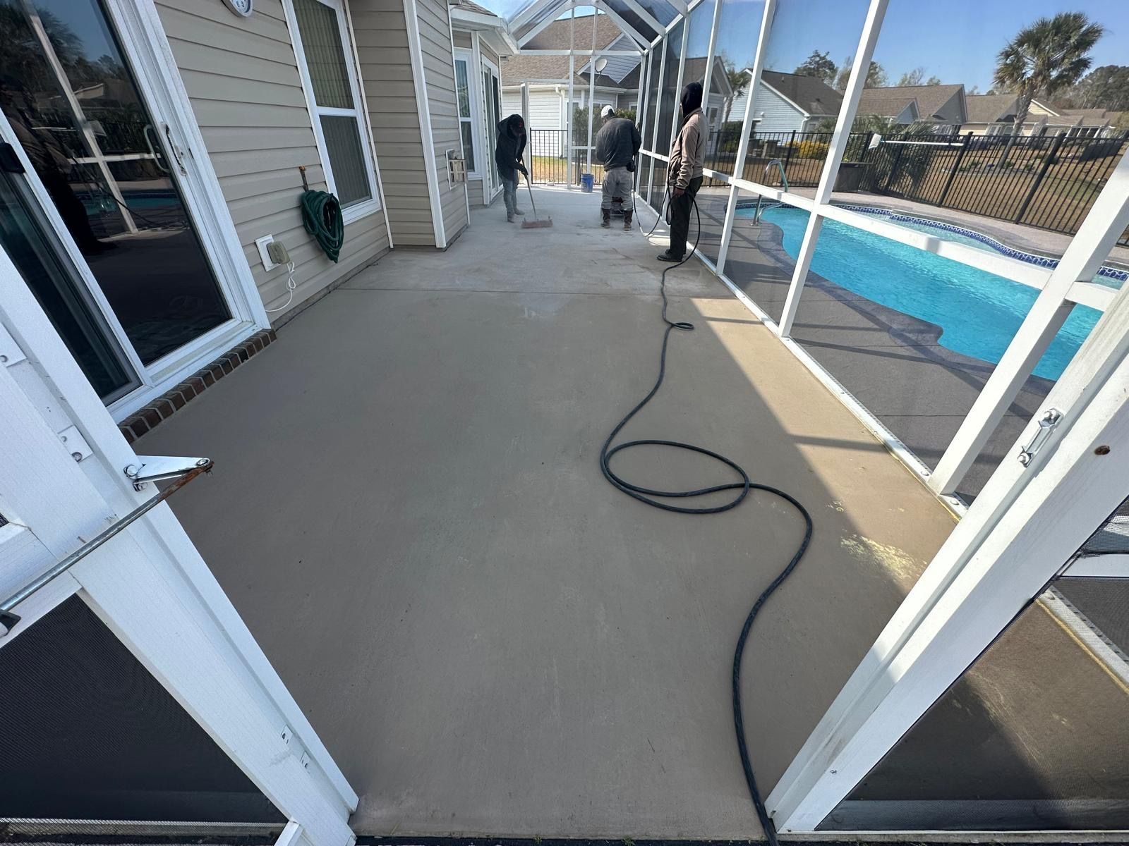 A man is standing on a screened in porch next to a pool.