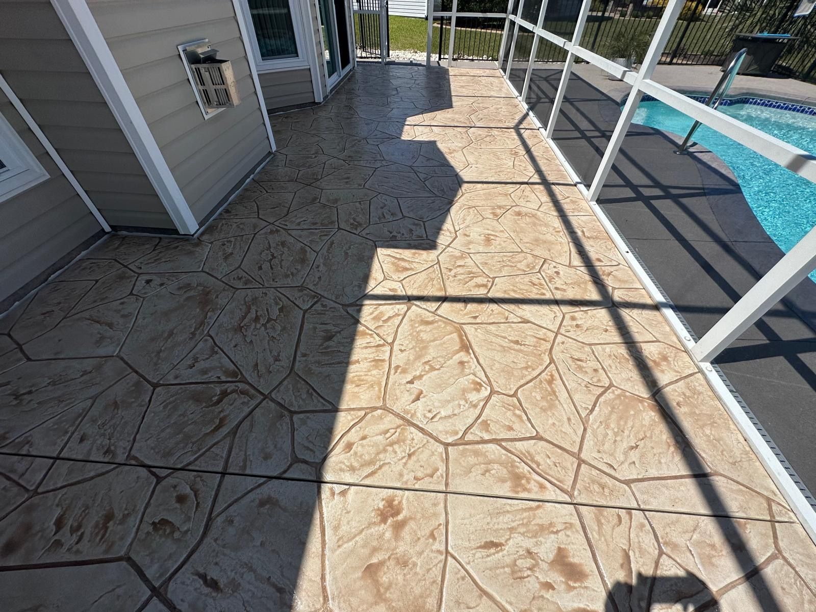 A patio with a concrete floor and a pool in the background.