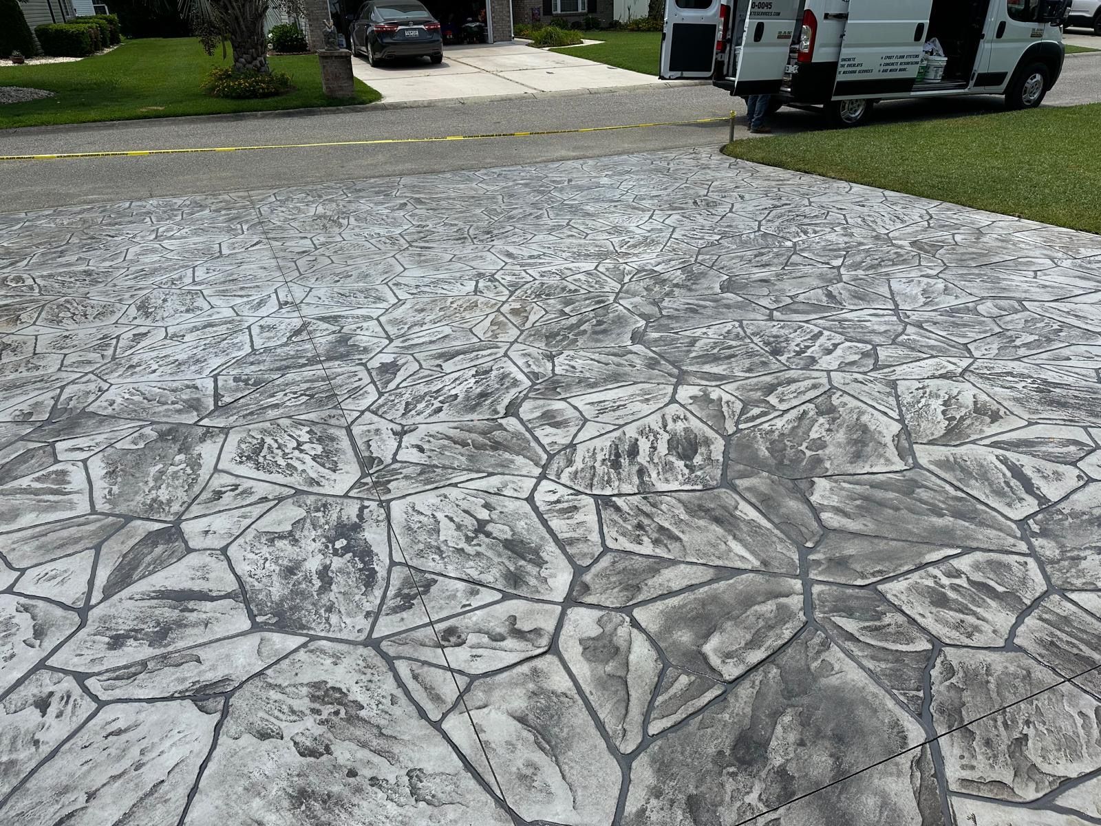 A white van is parked in a driveway next to a concrete driveway.